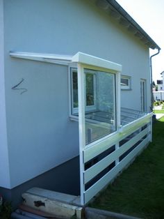 a small white house with windows on the front and side of it, sitting next to a grassy yard