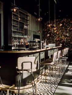 an empty bar with chairs and bottles on the wall