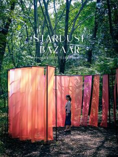 a person standing in front of some red and pink structures with trees behind them,