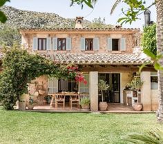 the house is surrounded by greenery and palm trees, with an outdoor dining area