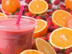 a smoothie with strawberries and oranges in the background