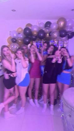 a group of young women standing next to each other in front of balloons and streamers