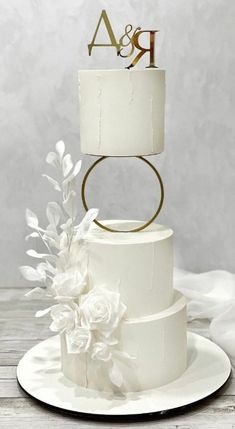 a white wedding cake with gold initials and flowers