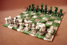 the chess board is made out of green and white marbles, with black pieces on each side