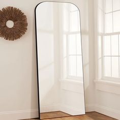 a mirror sitting on top of a wooden floor next to a window