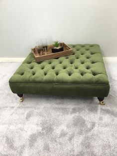 a green ottoman sitting on top of a carpeted floor next to a white wall