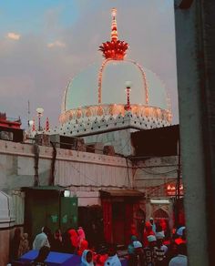 a group of people standing around in front of a building with lights on it's roof