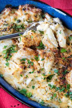 a blue dish filled with pasta and meat covered in parmesan cheese, garnished with herbs