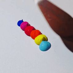 a person is holding their hand up to a toy caterpillar