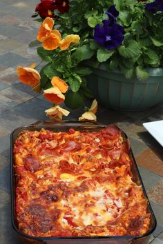 a pizza sitting on top of a pan next to flowers