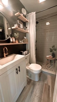 a white toilet sitting next to a sink in a bathroom under a large round mirror