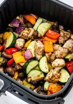 a pan filled with chicken and vegetables on top of a stovetop oven burner