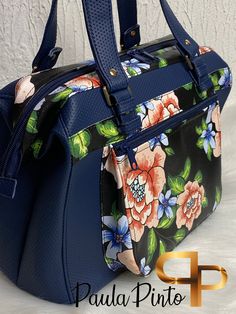 a blue floral handbag sitting on top of a white table