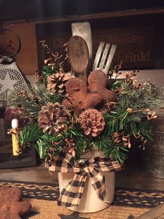 a christmas centerpiece with pine cones, greenery and two teddy bears in it