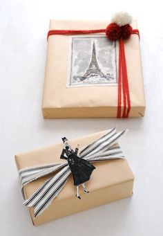 a wrapped present with a red ribbon on it and an eiffel tower in the background