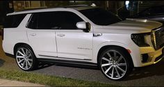 a white suv is parked on the side of the road at night time in front of a building