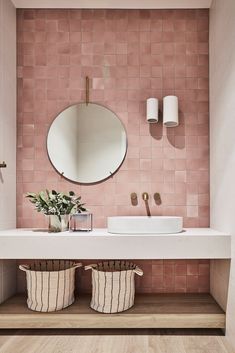 a bathroom with pink tiled walls and two round mirrors