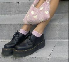 a woman sitting on the steps with her legs crossed wearing black shoes and pink heart socks