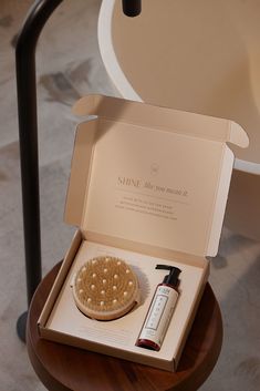 an open box containing a hair brush and lotion sitting on a table next to a chair