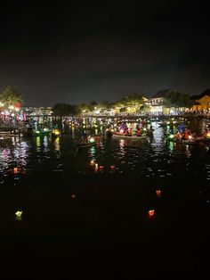 many small boats are floating in the water at night with colorful lights all around them