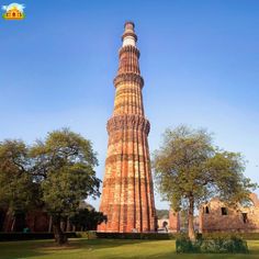 a tall brick tower sitting in the middle of a lush green field next to trees