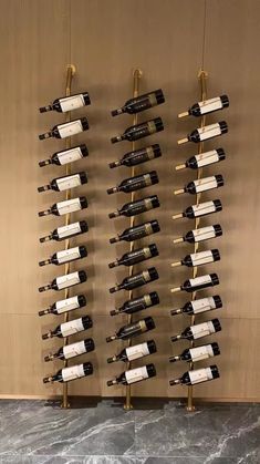 a bunch of wine bottles are hanging on the wall in front of a marble floor