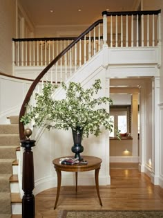 a vase with flowers sitting on top of a table in front of a stair case