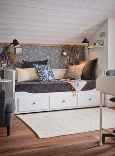 a small bed with drawers underneath it in a room that has wood floors and white walls