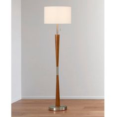 a lamp that is on top of a wooden floor in front of a white wall