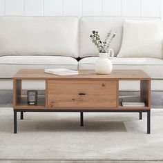 a living room with a couch, coffee table and vase on it's stand