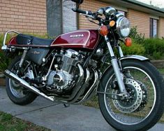 a red and black motorcycle parked in front of a brick building