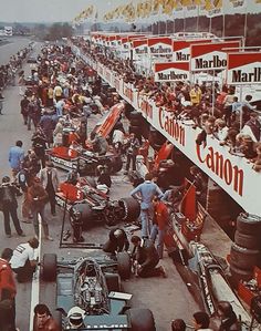 an old photo of a race track with many cars and people standing around the track