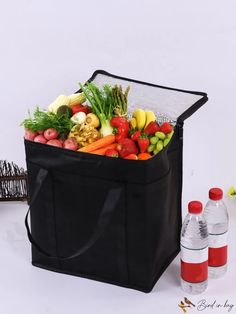 a black cooler bag filled with fresh fruits and vegetables next to a bottle of water