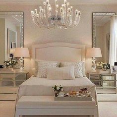 a white bed sitting in a bedroom next to two tables with lamps on top of them