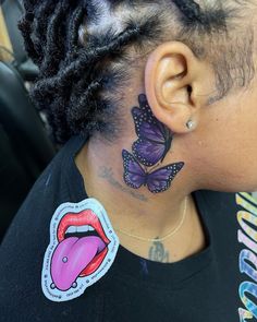 a woman with butterfly tattoos on her neck and behind her ear, looking at the camera