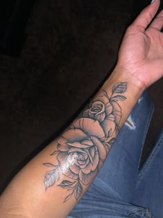 a woman's arm with a rose tattoo on it and her hand in the air