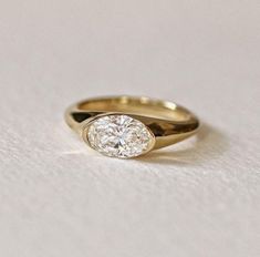 a yellow gold ring with a single diamond in the center on a white tablecloth