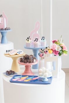 an assortment of desserts and pastries displayed on a cake stand in front of white walls