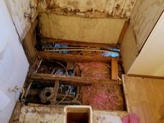 an unfinished bathroom with exposed plumbing and wood flooring on the walls, in need of remodeling