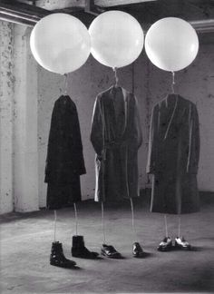 three balloons are hanging from the ceiling in front of two men's coats and shoes