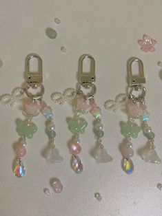 four charms are sitting on a table with water droplets and beads hanging from the clasps