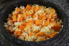 a bowl filled with rice and carrots sitting on top of a granite countertop