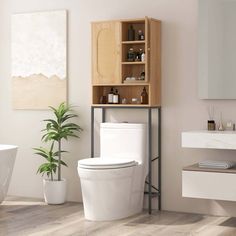 a white toilet sitting in a bathroom next to a sink and bathtub under a wooden cabinet