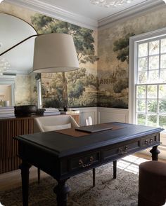 a room with a desk, chair and wallpapered walls in the background that has a painting on it