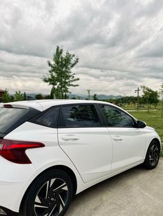 a white car parked on the side of a road next to a green grass covered field