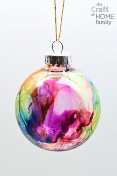 a colorful ornament hanging from a gold chain on a white background with the words craft and home family written below it