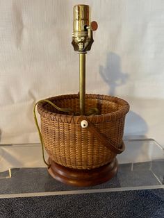 a wicker basket with a brass faucet on top and a wooden base