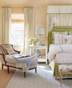 a bedroom with a bed, chair and ottoman in the corner next to two windows