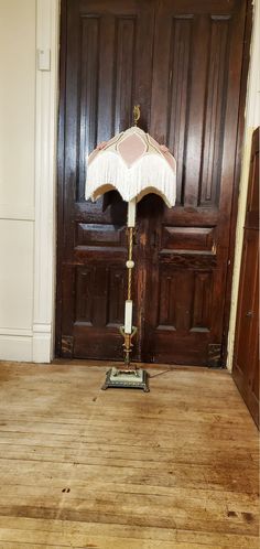 a floor lamp sitting on top of a wooden floor in front of a brown door