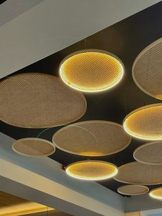 several circular lights hanging from the ceiling in an office building, with round wicker lamps above them